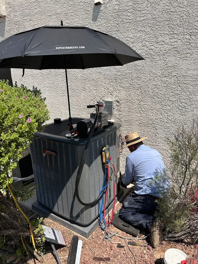 HVAC technician performing outdoor AC maintenance in Fort Lewis