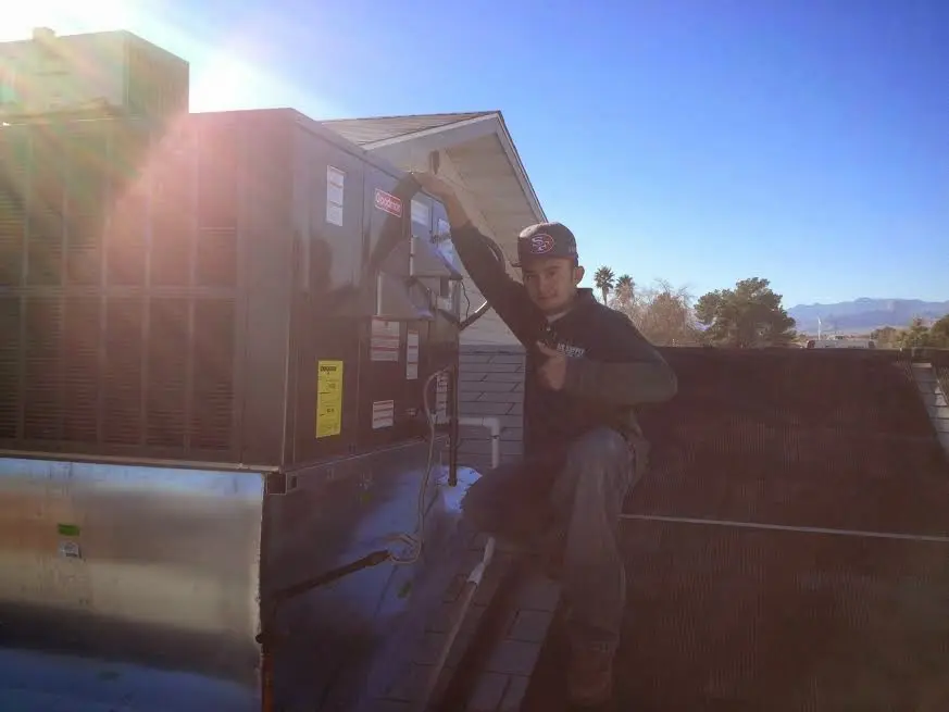 HVAC technician performing Boiler Repair on a rooftop unit in Fort Lewis